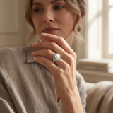 Bague en argent 925 ornée d'une perle blanche entourée de zircons, portée à la main.