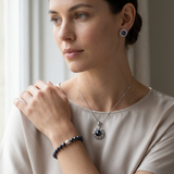 Parure collier, boucles et bracelet en perles noires portée par une femme.