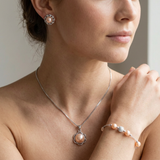 Parure collier, boucles d'oreilles et bracelet à perles roses portés.