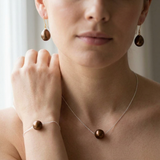 Parure collier, bracelet et boucles d'oreilles à perles chocolat portée sur cou, poignet et oreilles.