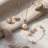 Parure collier, boucles d'oreilles et bracelet à perles roses sur chaîne argentée.