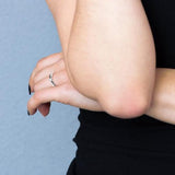 Bague solitaire croisée en argent 925 avec oxydes de zirconium blancs et noirs, portée à la main.